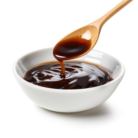 Dunkler Kokosnektar in weißer Schale, der von einem Holzlöffel fließt – natürliche vegane Süße für Desserts und Getränke.