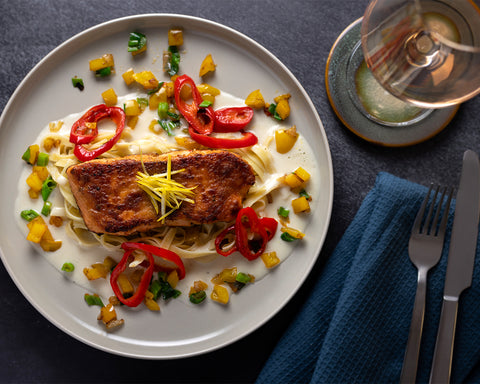 Marinierter Lachs in Aminos Gewürzsauce auf Teller mit Weinglas