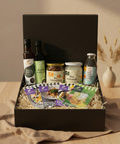Geschenkbox mit ausgewählten Kumaio-Produkten: Bio Kokos Aminos, Bio Kokoschips Natur, Bio Kokosöl und Bio King Coconut Water, ergänzt durch Rezept- und Produktkarten, dekorativ arrangiert in schwarzer Box mit Holzwolle.