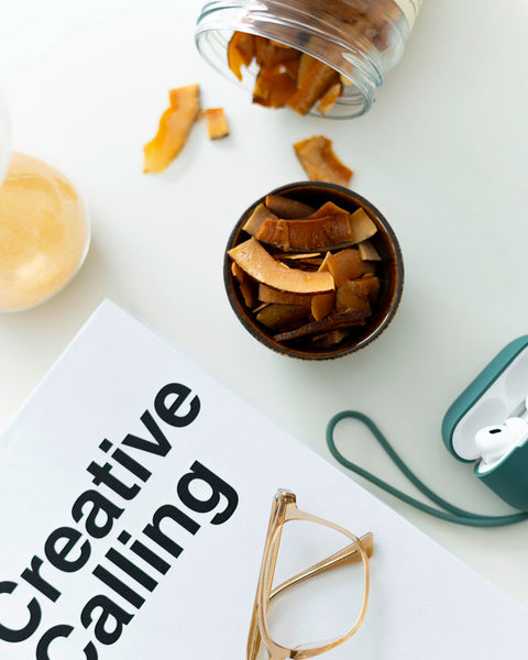 Schale mit Kokoschips neben einem Buch, einer Brille und Kopfhörern – eine entspannte Snack-Szene für kreative Pausen.