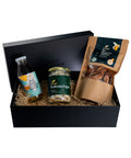 Schwarze Geschenkbox mit drei Bio-Produkten: eine Flasche King Coconut Water, ein Glas Kokoschips Natur und eine Tüte getrocknete Bio-Bananenhälften. Die Produkte sind dekorativ auf Holzwolle gebettet.