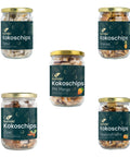 Fünf Gläser mit verschiedenen Sorten Kumaios Kokoschips, darunter Natur, Ananas, Mango, Zimt und Passionsfrucht.