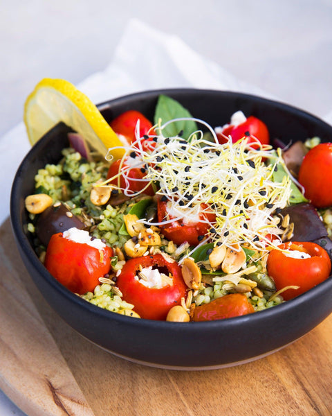 Bunte Bowl mit gefüllten Peppadew roten Kirschpaprika, Couscous, Sprossen und Nüssen als gesunder Snack.